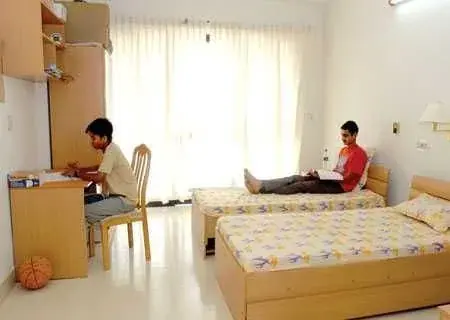 A boys’ hostel room with beds and study desks
