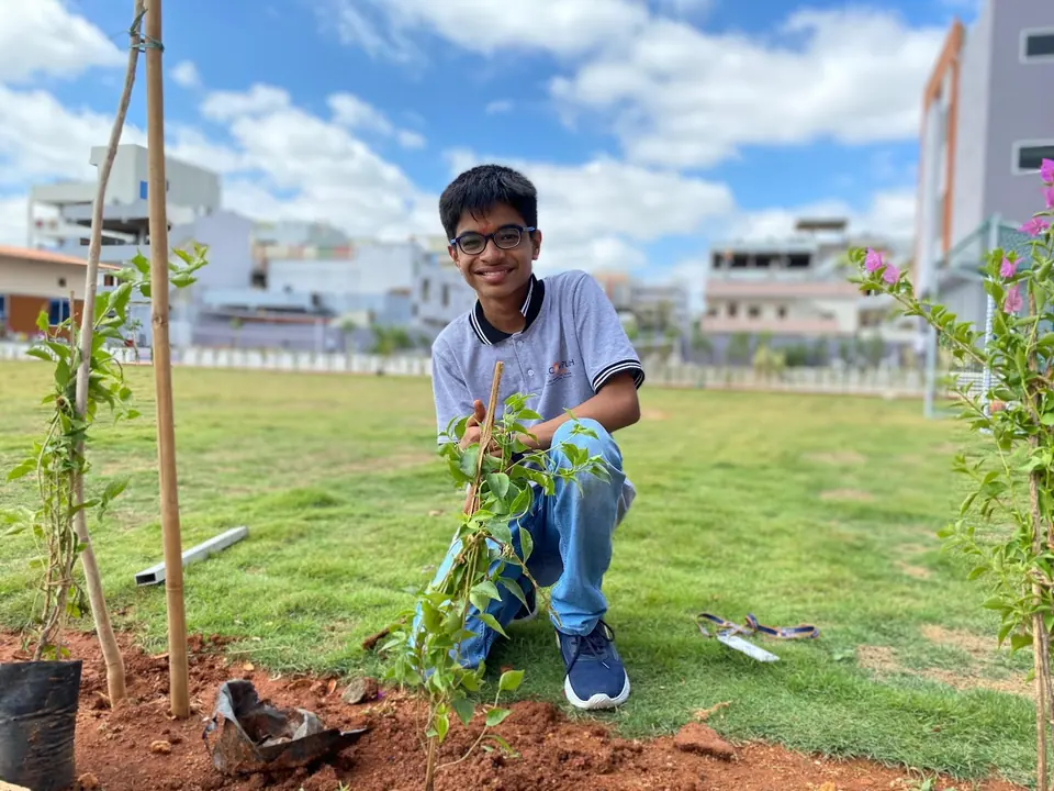 A student smiling after planting a sapling